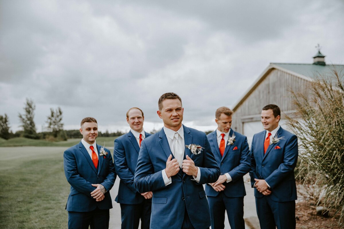 Groom standing in front of his groomsmen for wedding portrait for rustic farm wedding in Exeter, ON