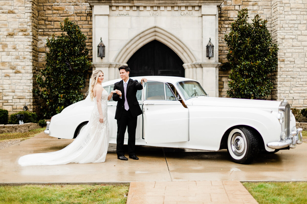 bride and groom outside castle venue standing beside Rolls Royce