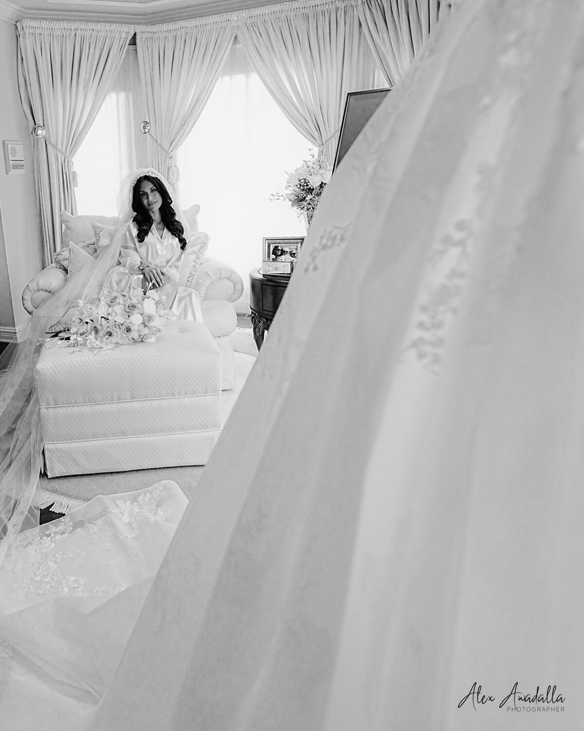 A bride, in the midst of getting ready, gazes admiringly at her wedding dress. This image captures the anticipation and elegance of the moment, showcasing her attention to detail and the beauty of her bridal attire in a personal and intimate setting.