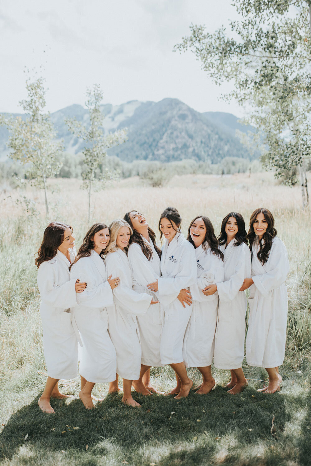 Bride and bridal party in white robes before the outdoor mountain wedding