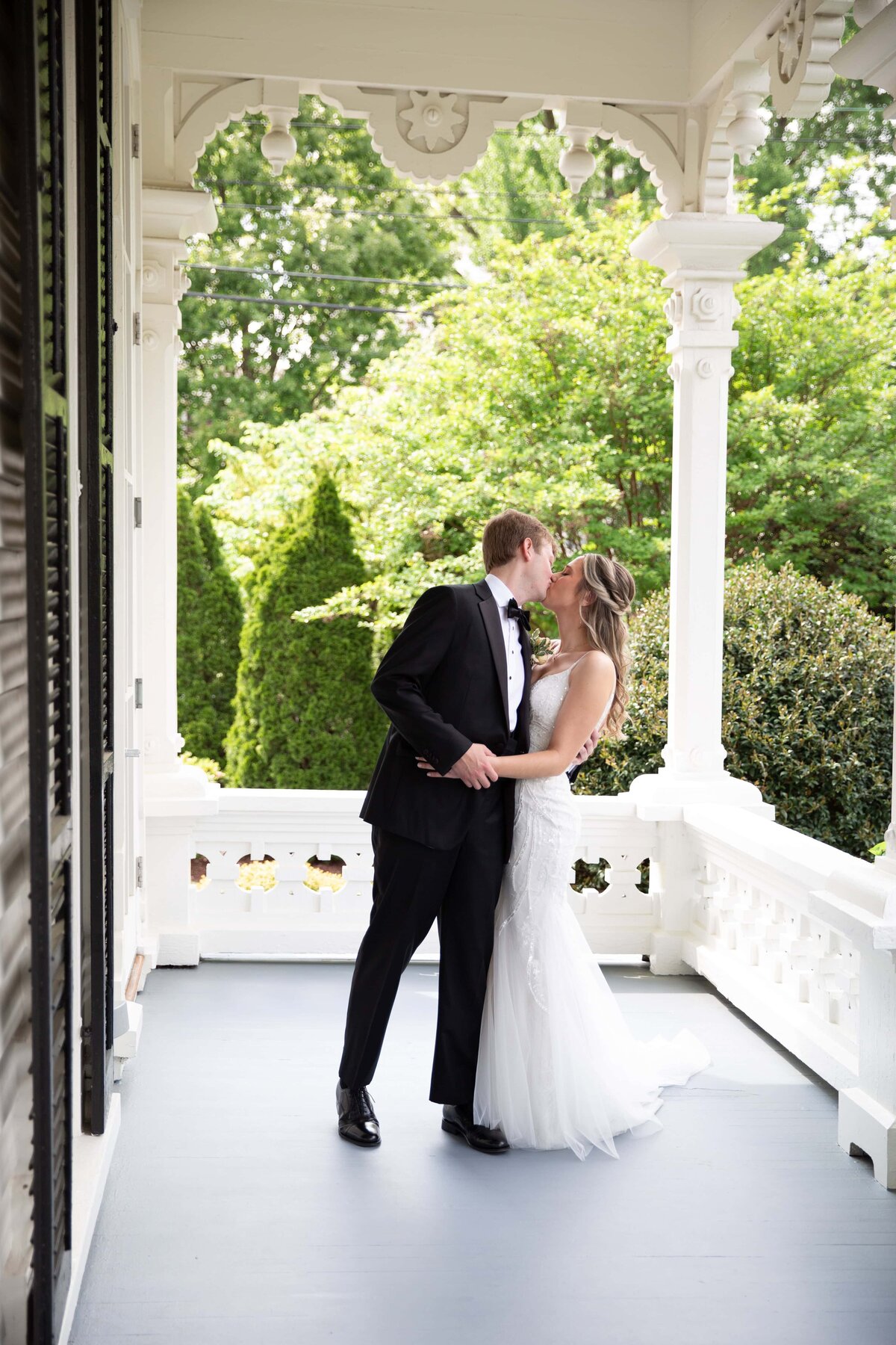 Bride and groom sharing a kiss on the porch of the Merrimon-Wynne House in downtown Raleigh, NC