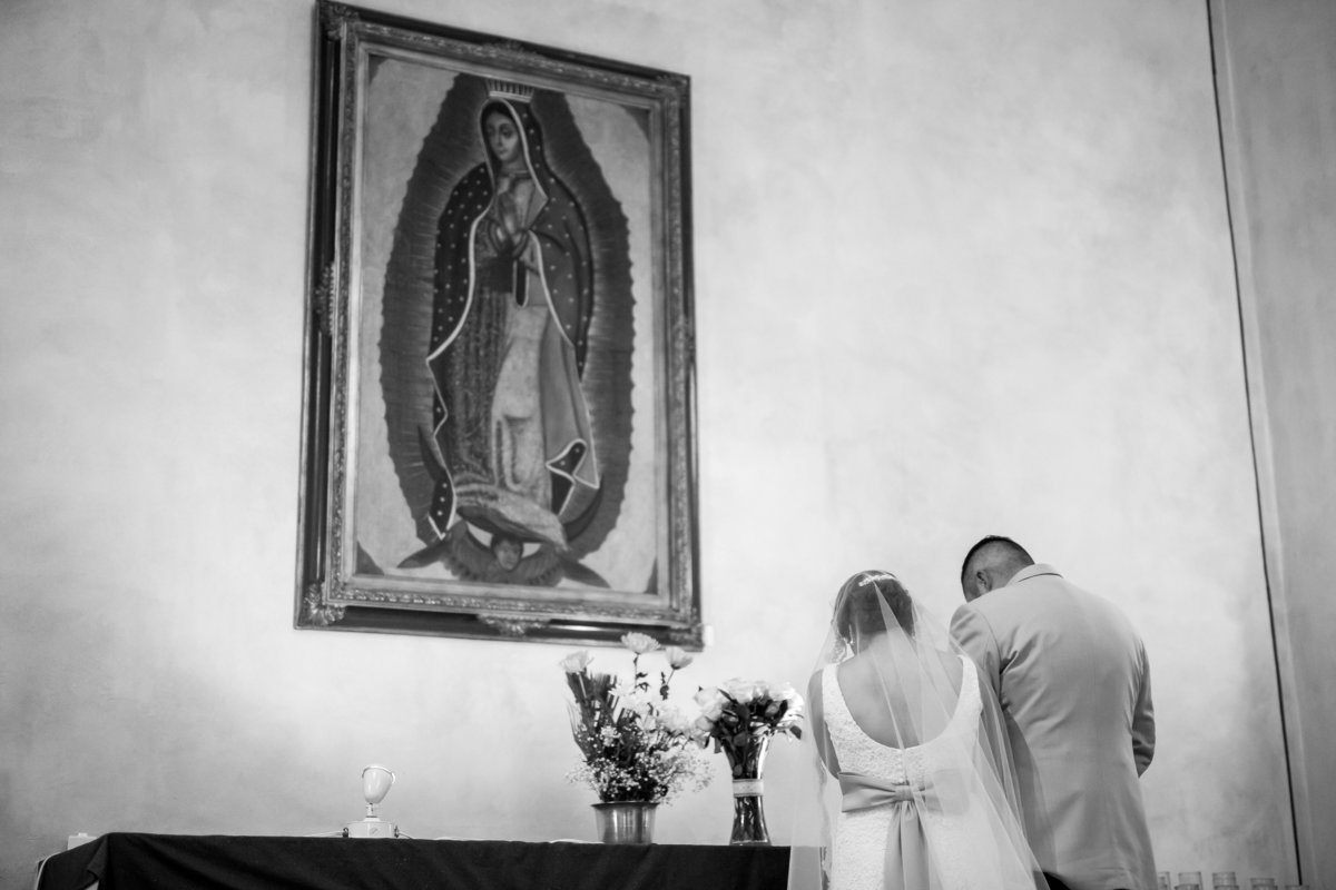 bride and groom giving roses to mary in catholic wedding ceremony at mission san jose san antonio