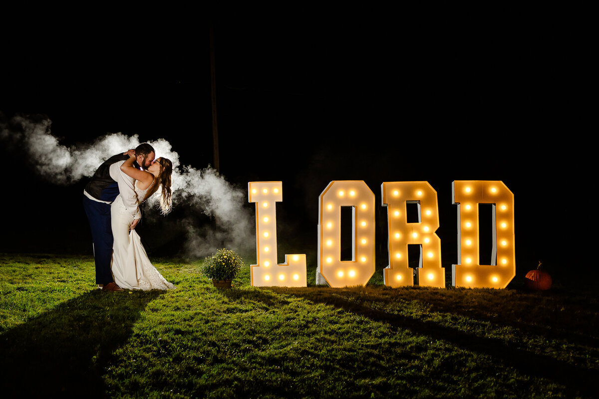 Bride and groom kissing next to their marquee letters by NH Wedding Photographer Lisa Smith Photography