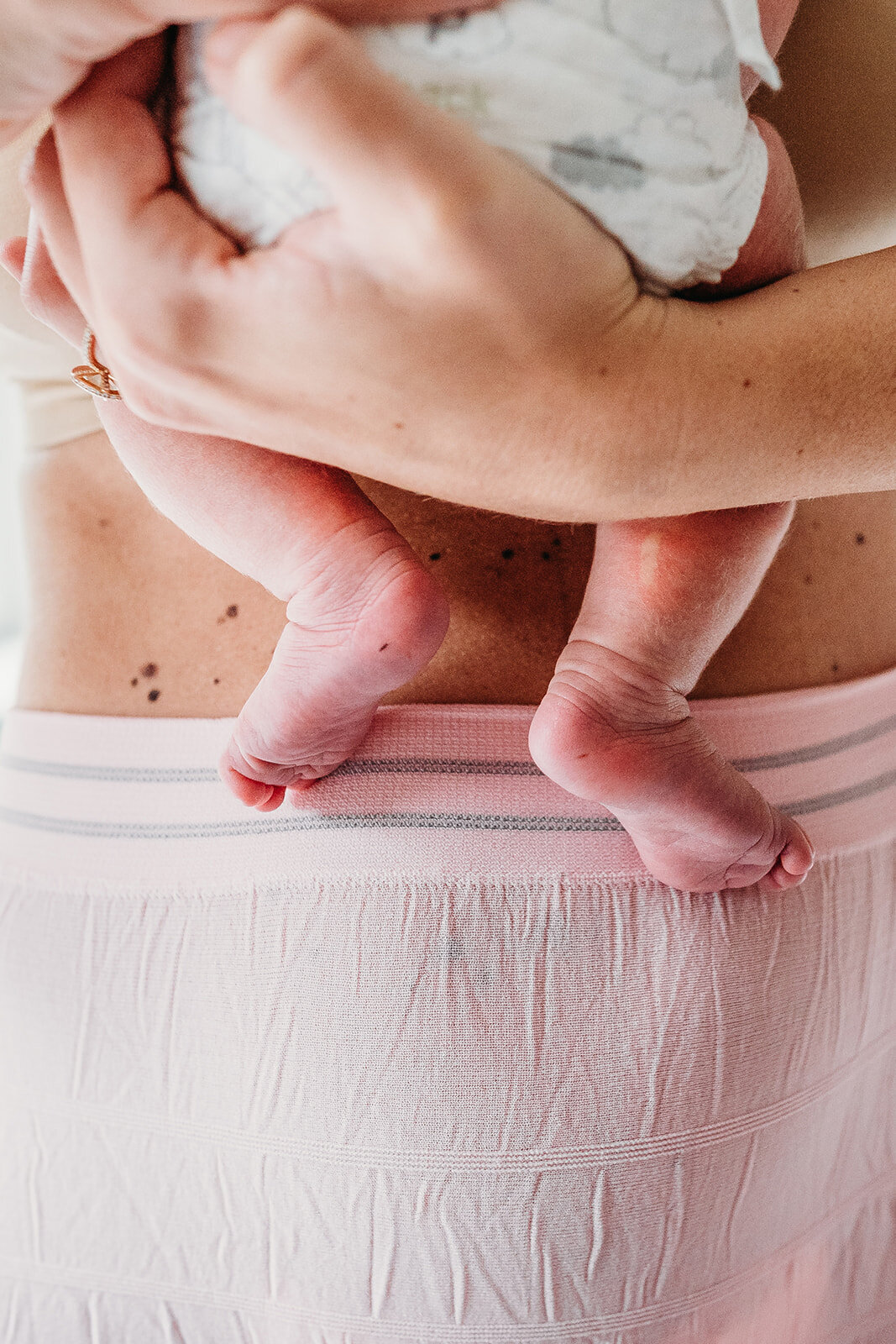 baby's feet dangle on top of post partum underwear