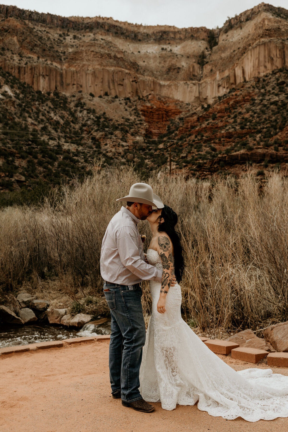 bride and grooms first kiss in front of Jemez Springs red rocks