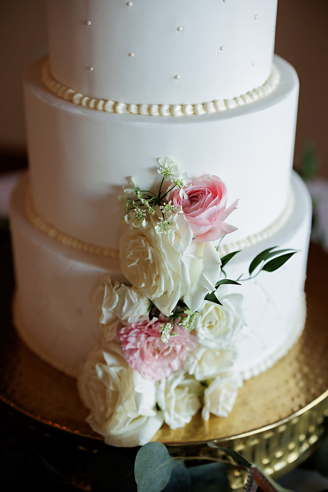 White wedding cake with pink or white flowers.