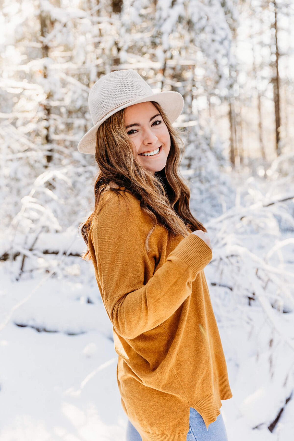 girl in a white hat playing with her hair during her winter senior photo session with Ashley Kalbus Photography