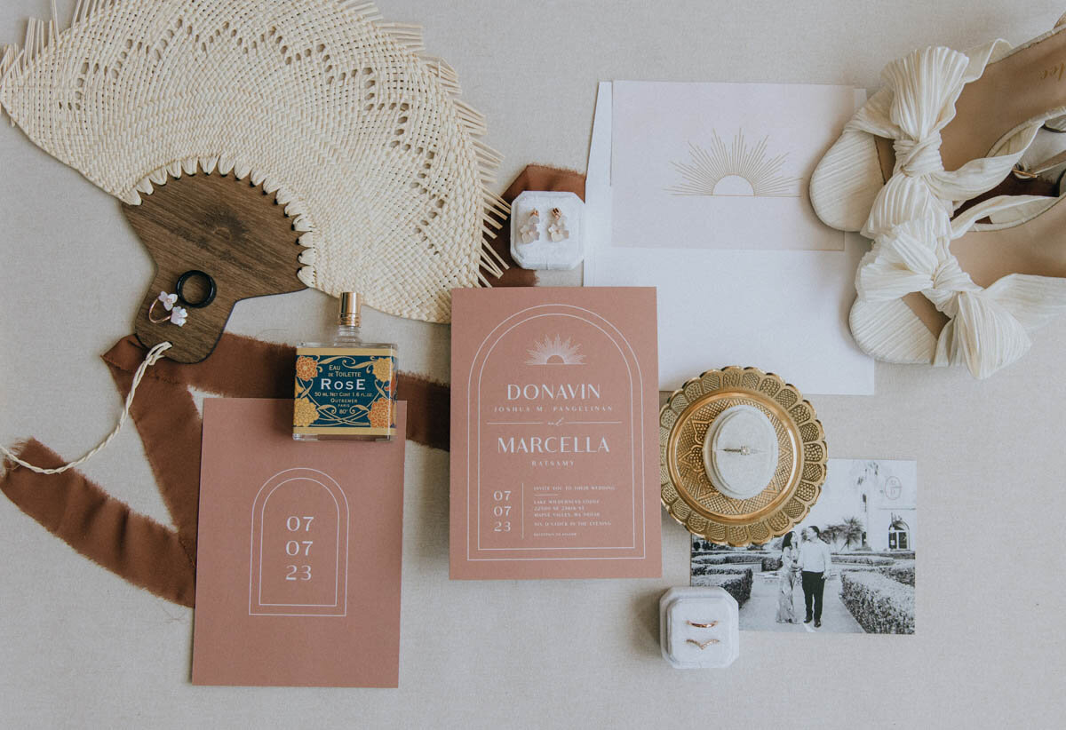 flat lay arrangement of wedding invitation suite, ring, and shoes