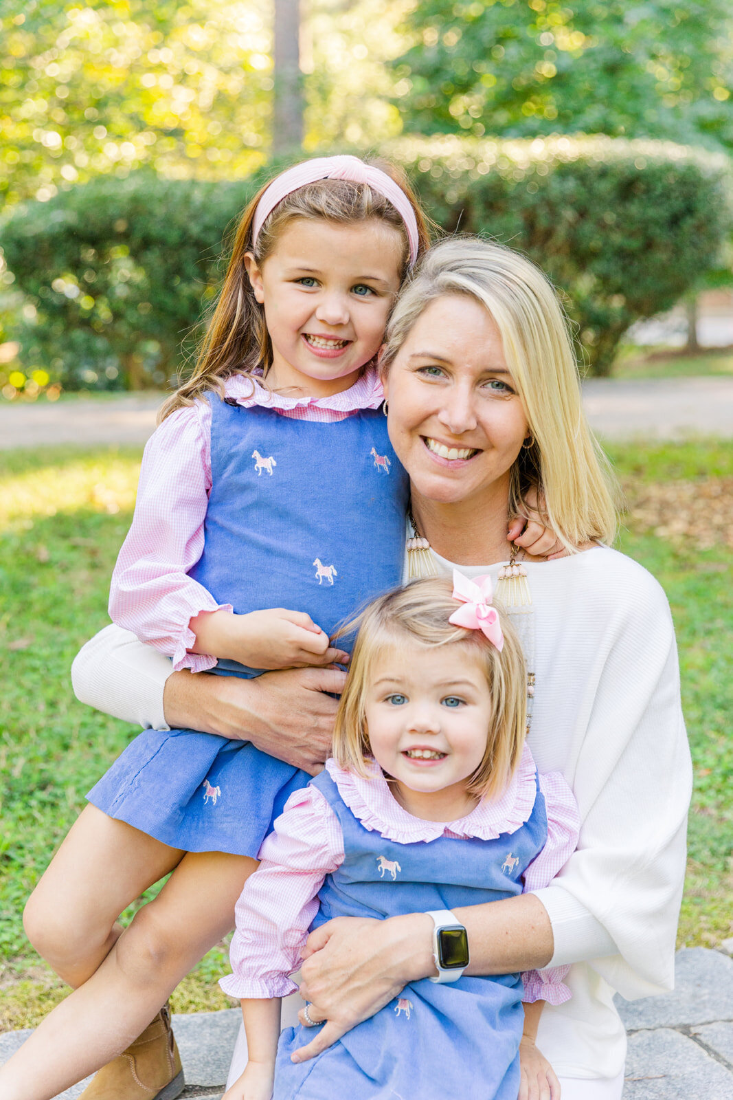 mum wearing white hugging toddler daugters wearing pink and blue in a park Buckhead Atlanta