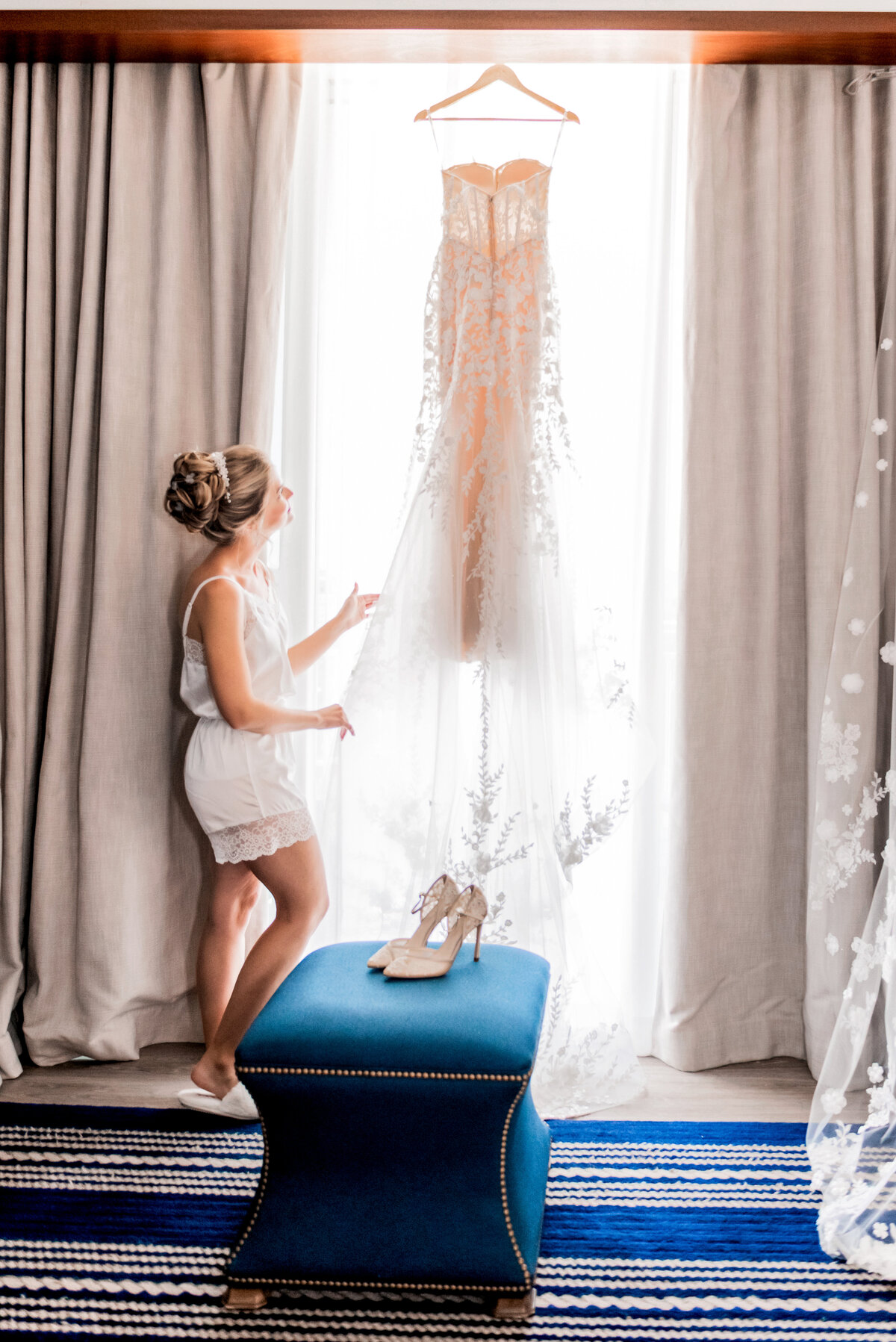 bride looking up at her dress in hotel