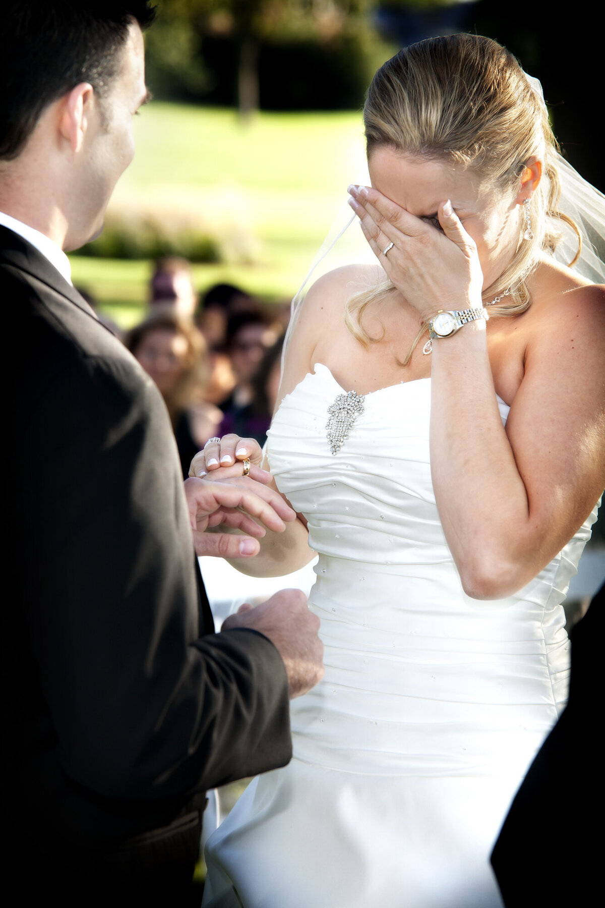 A bride cries while exchanging vows during an outdoor wedding ceremony.