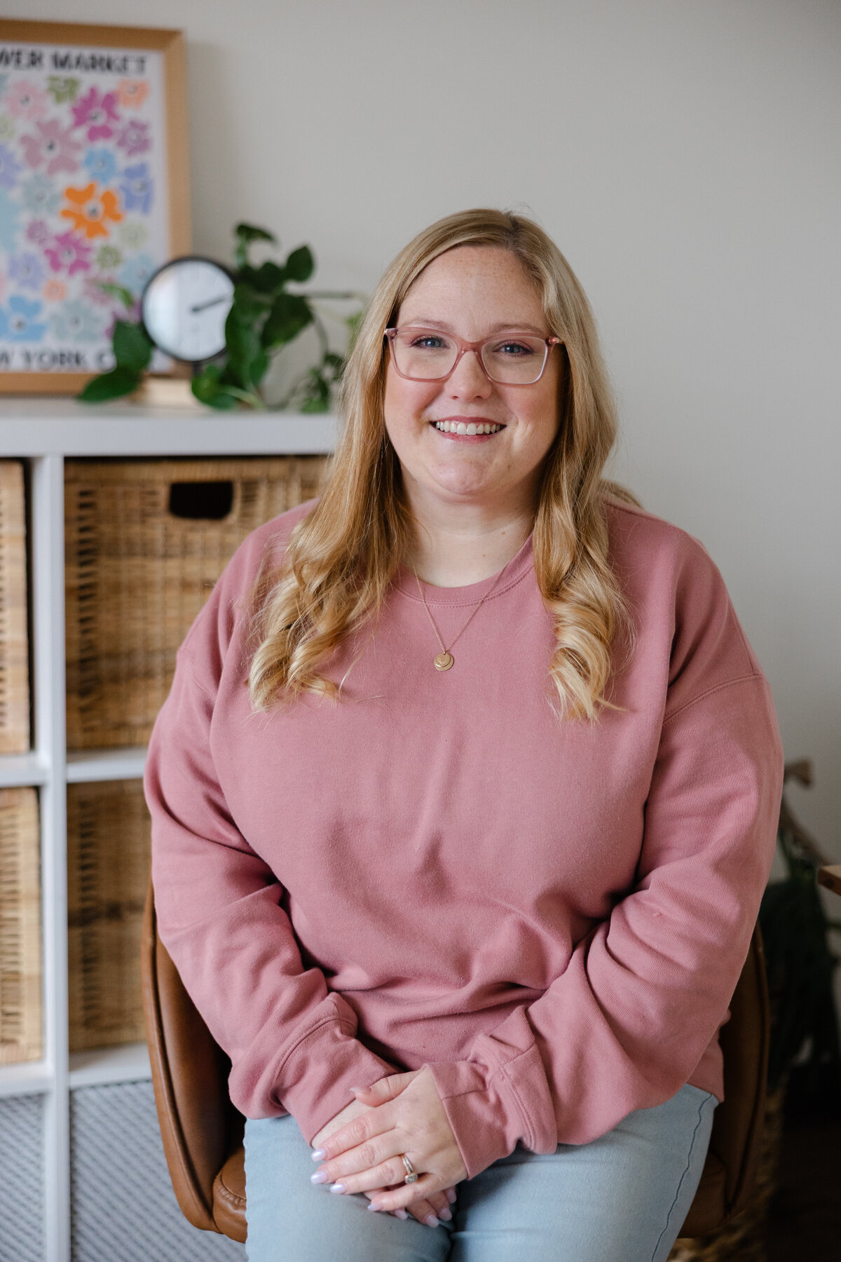Woman with blonde hair in pink sweater smiling while seated indoors. Photograph by Yucaipa branding photographer Kaitlyn Dawn Photography.