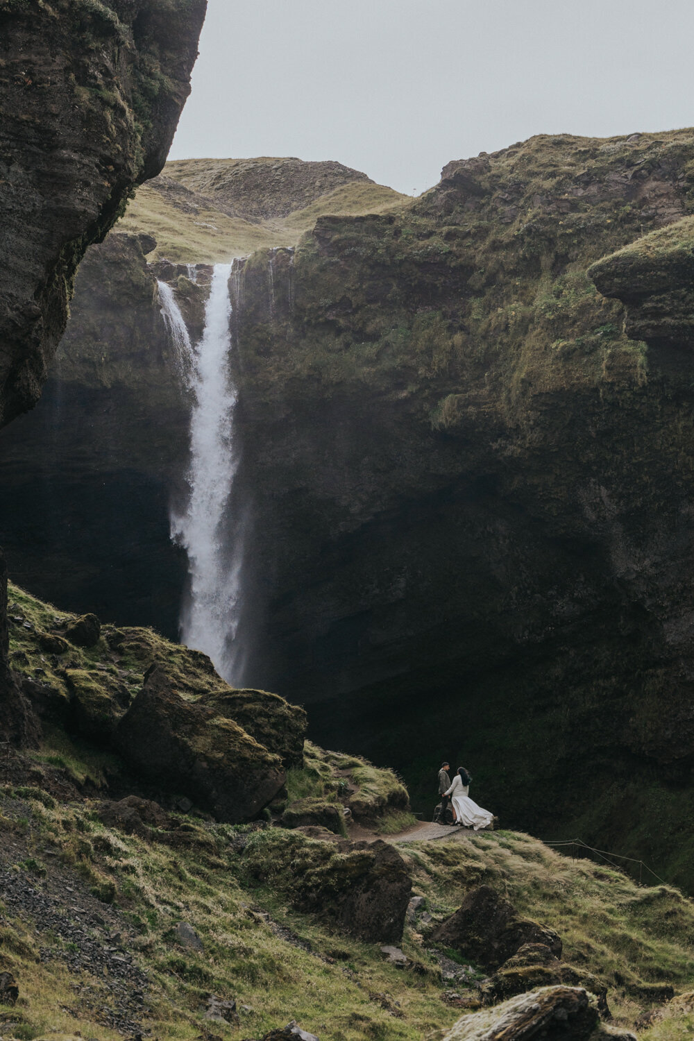 Walking side by side, the couple enjoys the serene beauty of a secluded waterfall in the heart of Iceland 