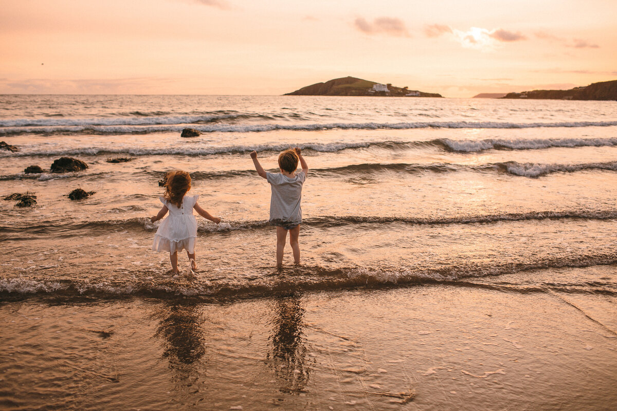 Two children play in the sea at sunset