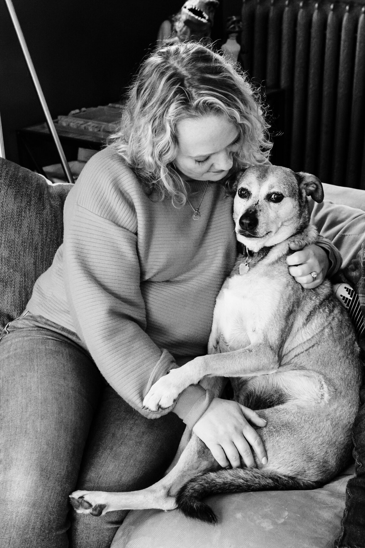 A woman cuddles with a dog on a couch.