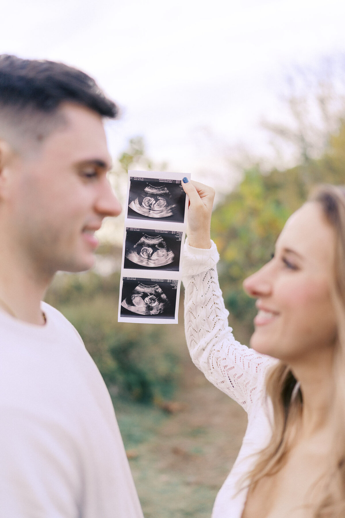 pregnant woman and her husband hold up ultrasounds for maternity photos in knoxville tennessee