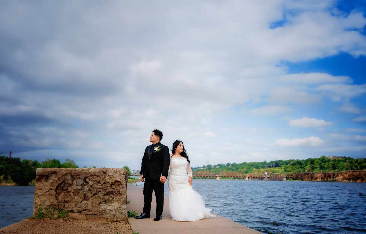 bride and groom posing near riverwalk
