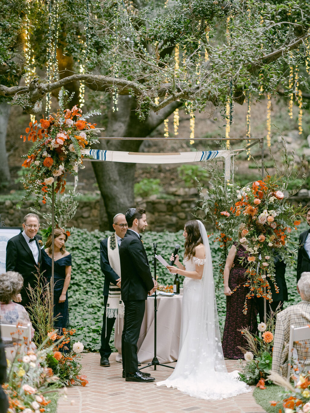 bride and groom under chuppah and tree of lights