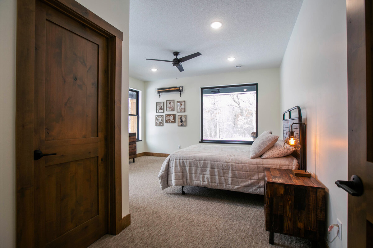 Spacious secondary bedroom in custom Elk River home with dark wood accents and neutral tones