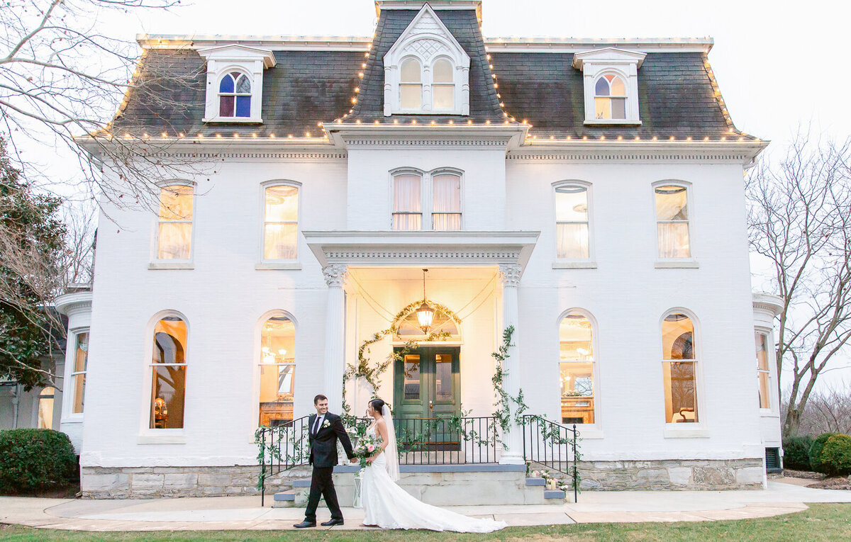 Groom walking with bride in front of Ceresville Mansion in Frederick, Maryland in the winter. Captured by Bethany Aubre Photography.