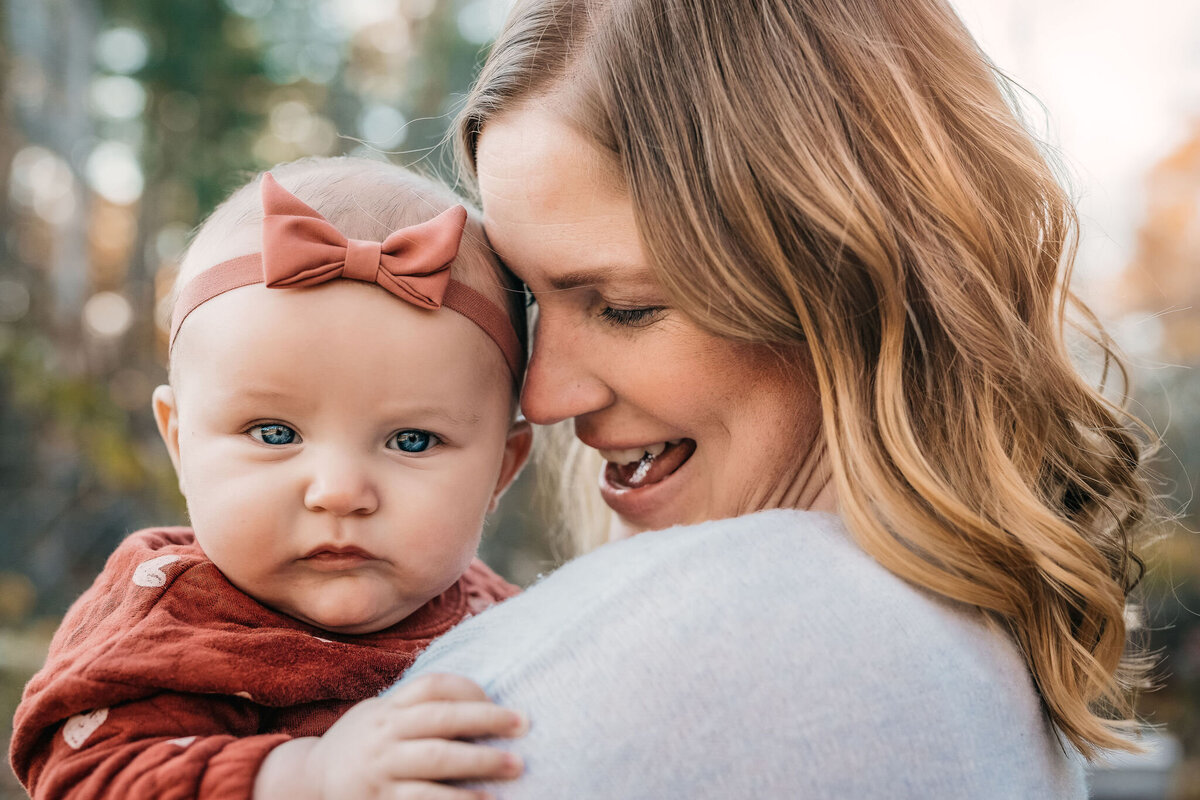 mom holding baby girl with pink headband at family photo session by lisa smith photography