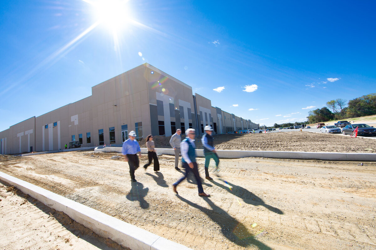 Large new construction with 5 blurred figures in motion walking in front of it