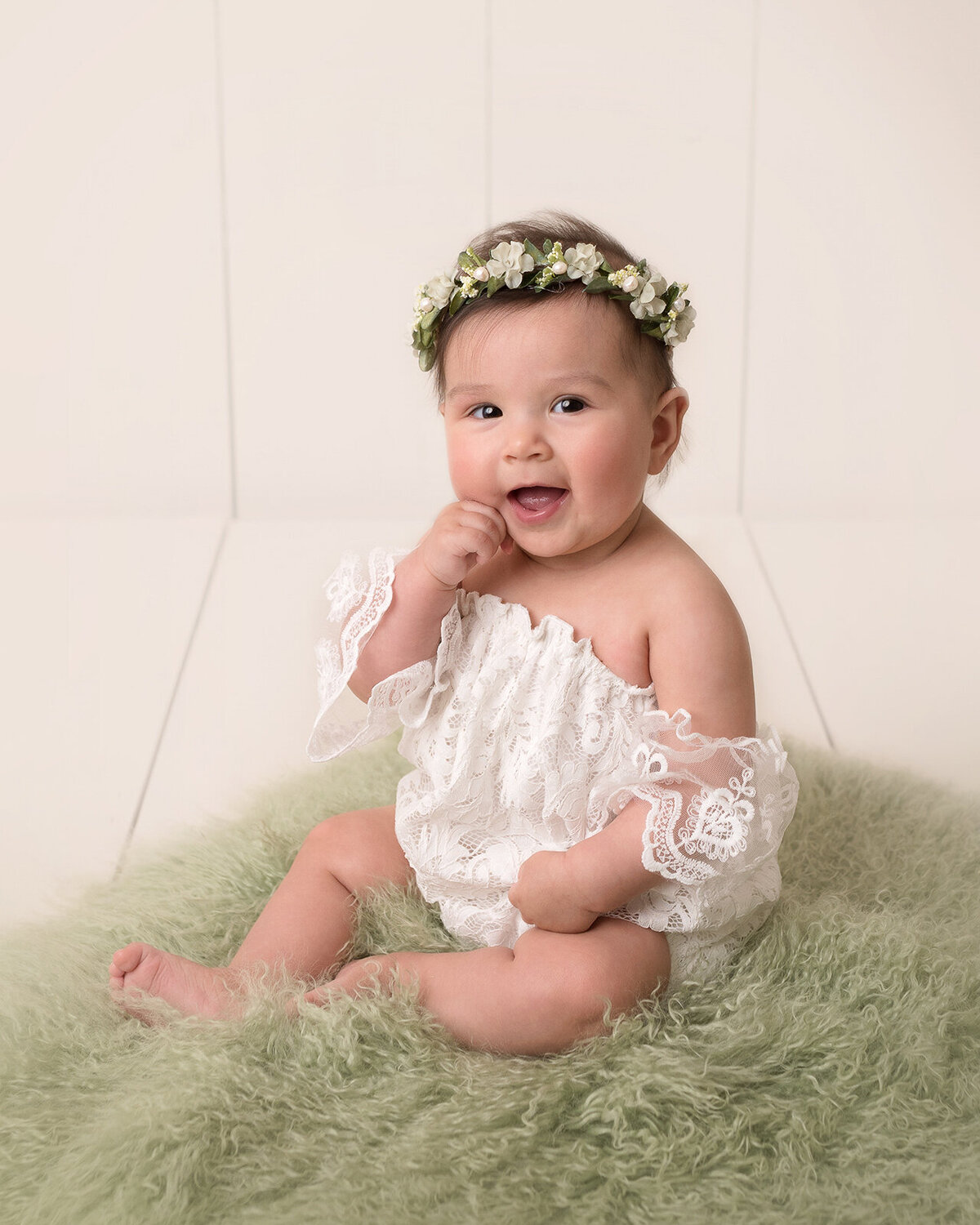 Little baby girl in green furry background and white flower headdress