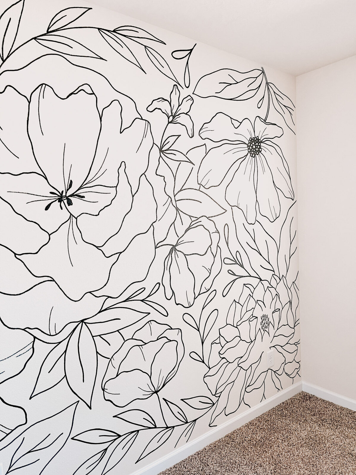 A modern bedroom wall in white with black florals hand drawn on it representing full service design and calligraphy by Life in Letters.