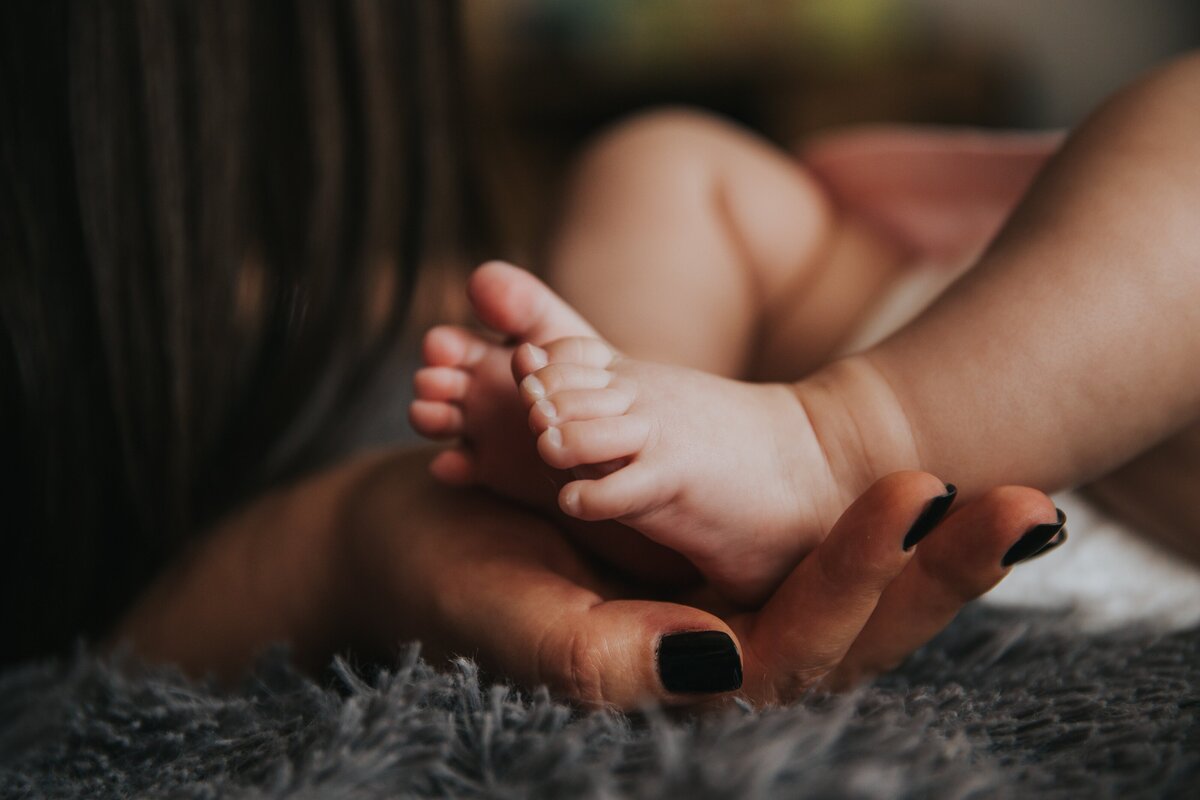 A newborn's feet held gently in a mother's loving hand