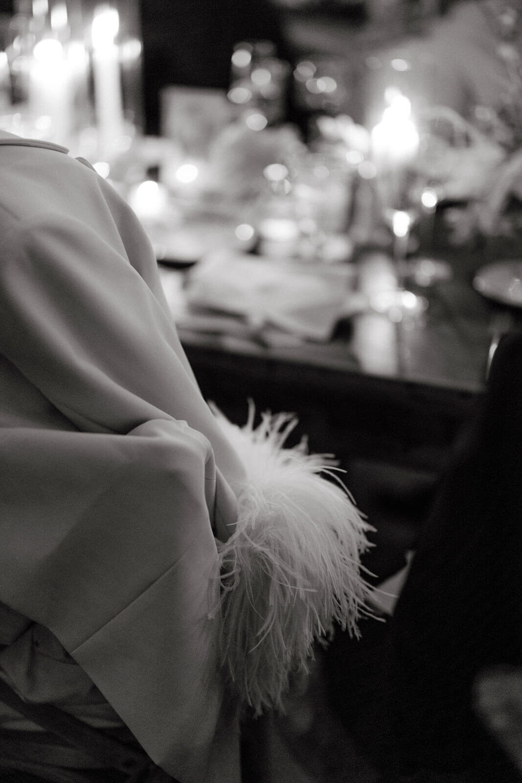 A back view of the bride, wearing a coat with fur, sitting at the elegant dining table, at The Ausable Club, NY. Image by Jenny Fu Studio