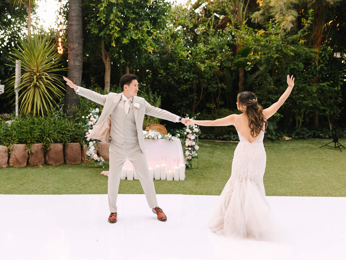 A couple shares their first dance outdoors on a white floor, surrounded by lush greenery at Hartley Botanica.