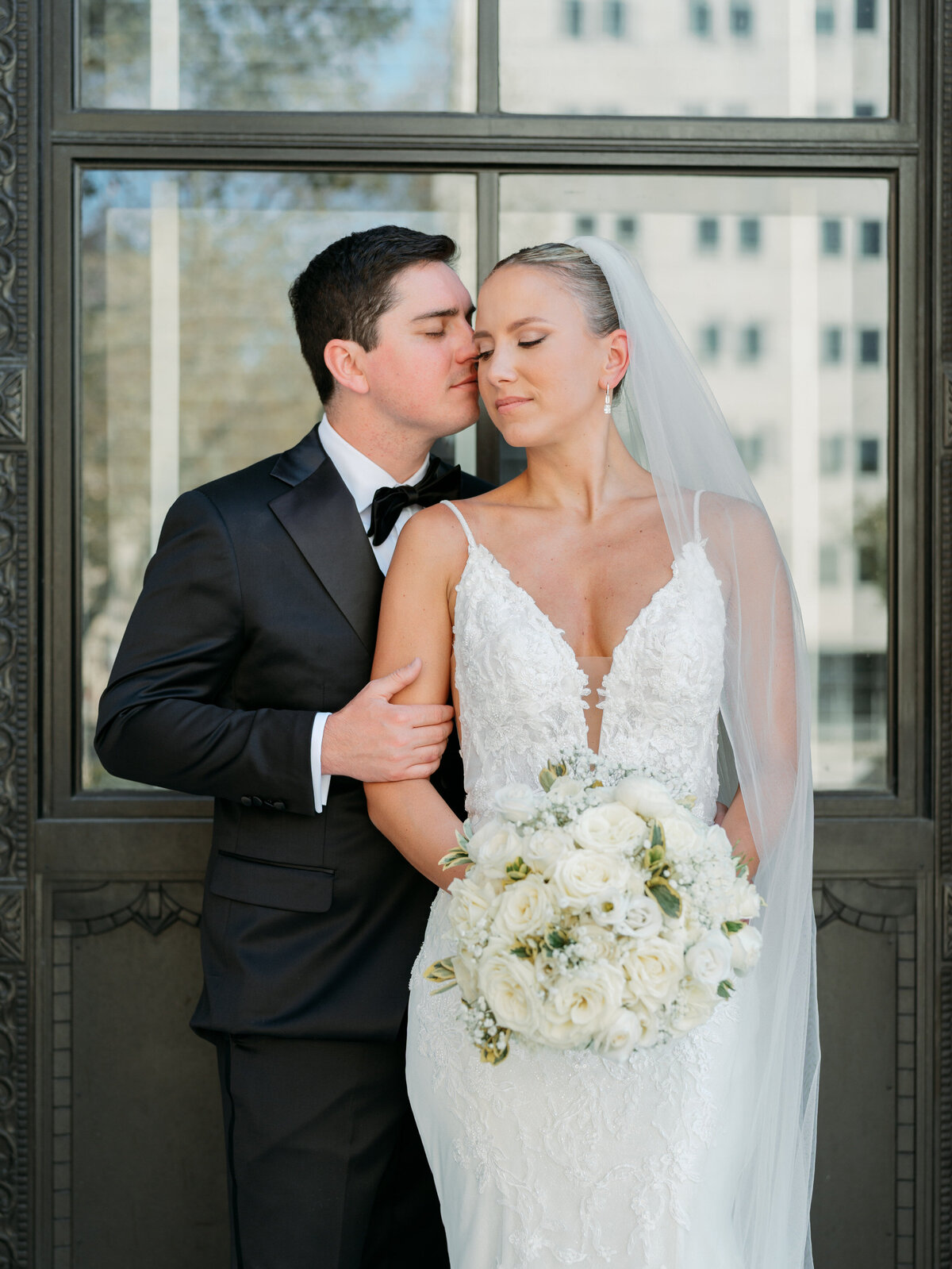 Groom kisses bride's temple during wedding portraits, a soft, romantic shot by Philadelphia wedding photographer.