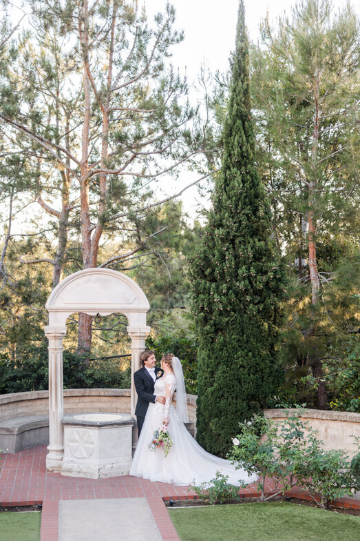 bride and groom by wishing well at the Prado in Balboa Park San Diego