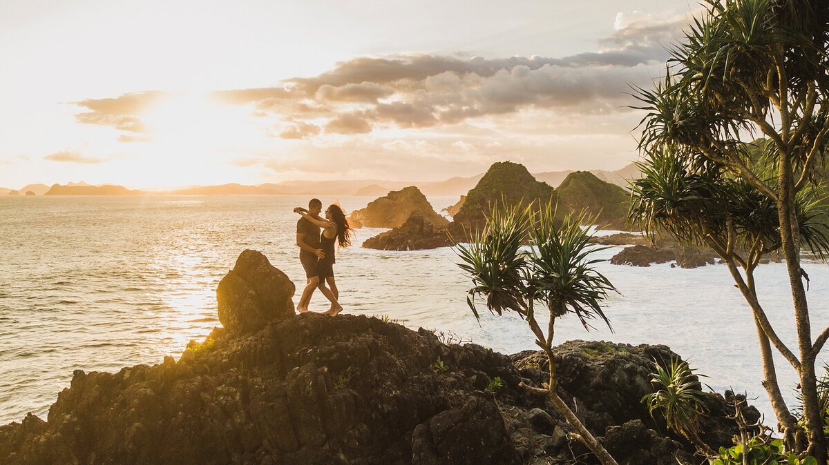 bride and groom hug atop a mountainside cliff overlooking the ocean in Bali