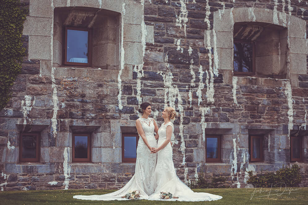 A couple of brides standing next to each other in front of a building