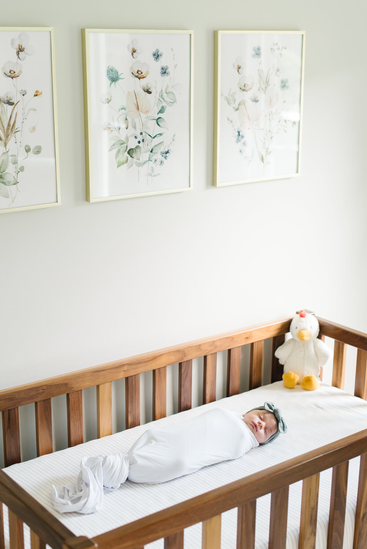 Baby swaddled in wooden crib in nursery