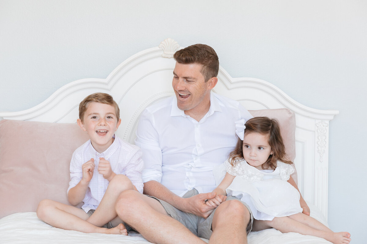 A dad sitting on a bed with his two kids
