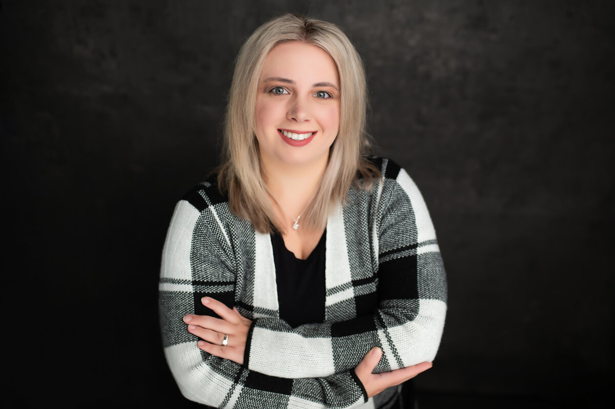 A headshot of a business woman posing in our Waukesha studio wearing a black and white flannel jacket.