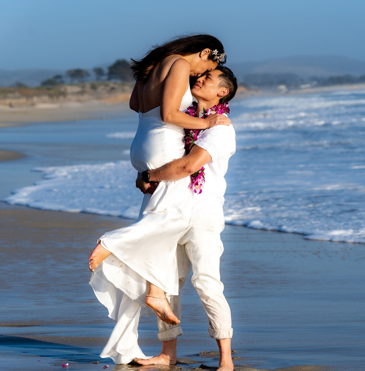 Couple dressed in white at the beach following wedding ceremony.