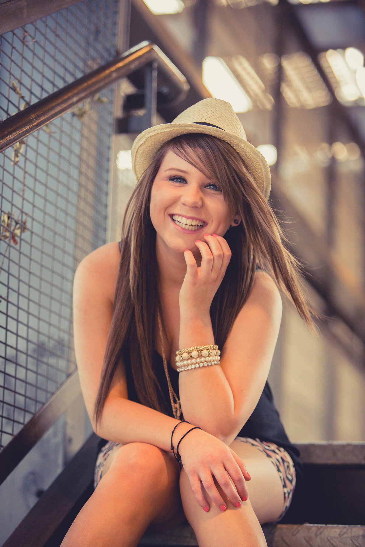 girl smiling and sitting on stairs wearing hat by San Antonio high school senior photographer