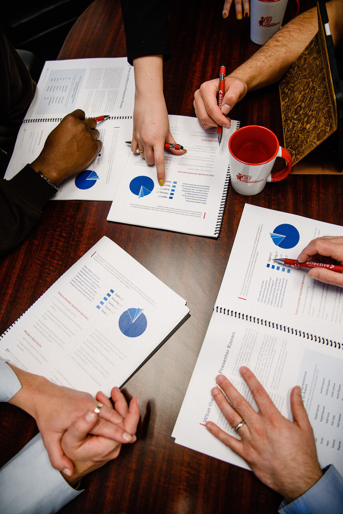 A stock photographer and product photographer in Denver takes a photo of a business meeting with all hands in over paperwork for a brand photo shoot for branding pictures and brand photos.
