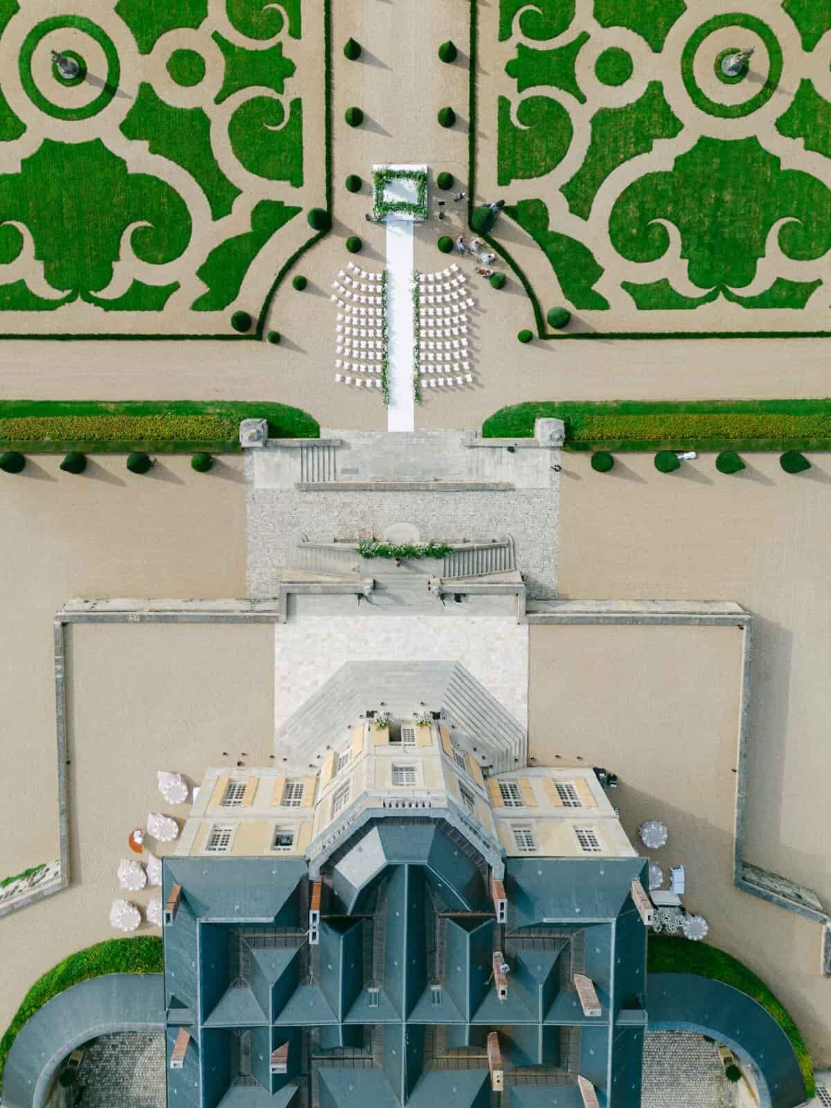 Aerial view of a château and symmetrical French gardens set up for a luxury wedding, by Paris wedding photographer Thomas Raboteur