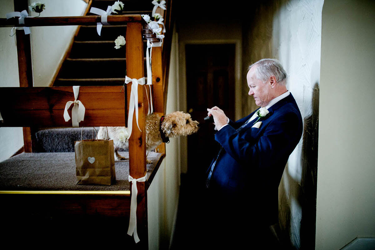 Father of the bride taking a photo of his dog who keeps creeping closer