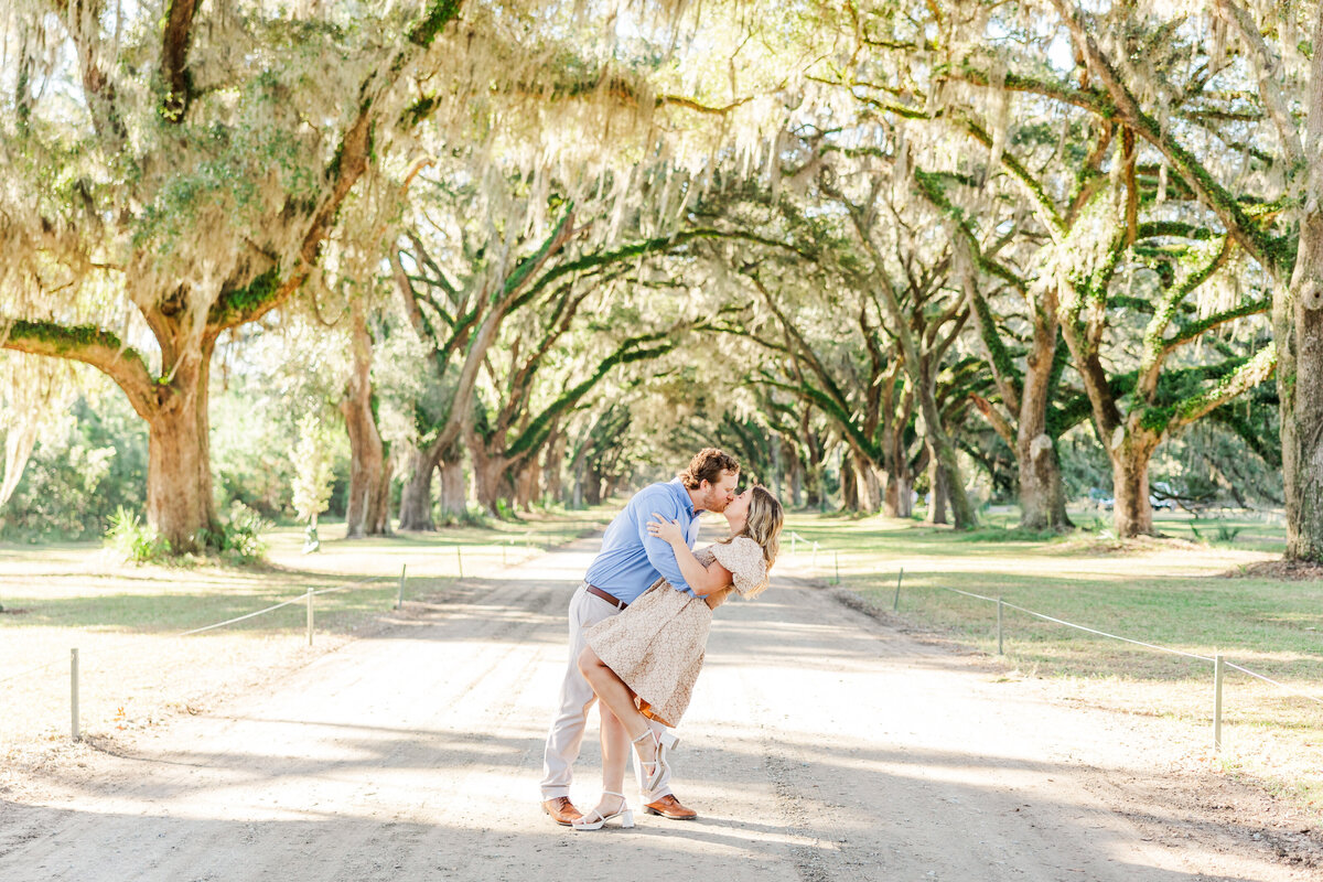 engaged couple kissing underneath trees