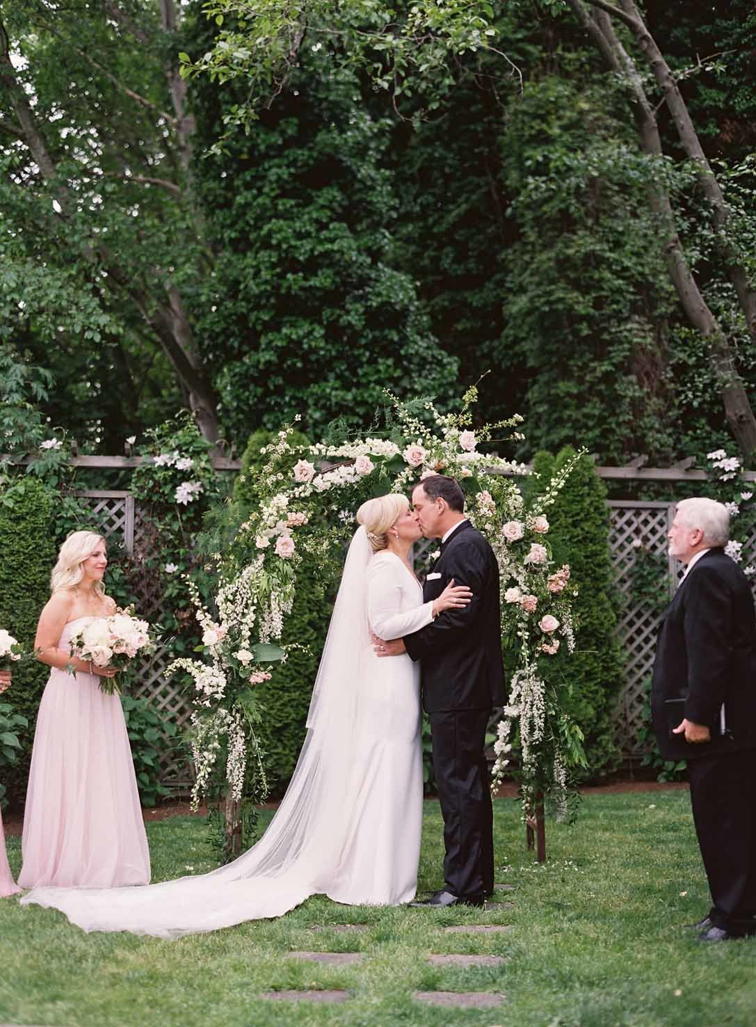 first kiss at Admiral's house Seattle wedding in garden with flower arbor