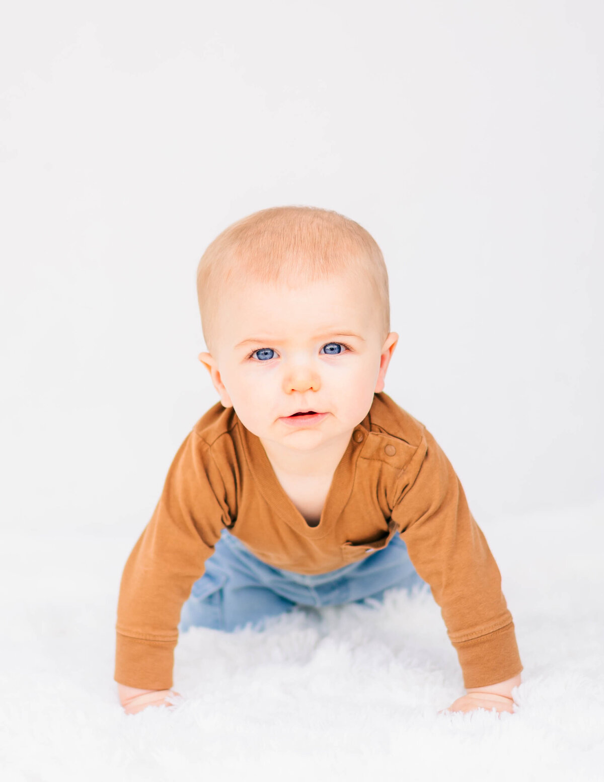 Baby boy sitting upright, bright white background with soft natural light