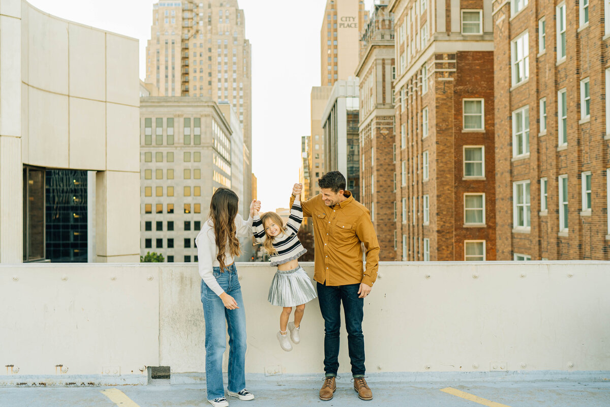 dad and mom pose with daughter in downtown oklahoma city during family photography session