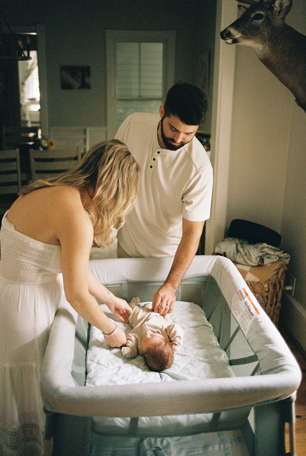 Couple putting a baby to bed during an at home new born session in upstate new york