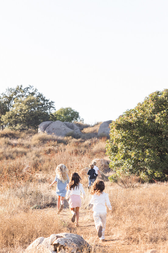 children-running-up-hill-family-of-four-sitting-on-rock-wrights-field-san-diego