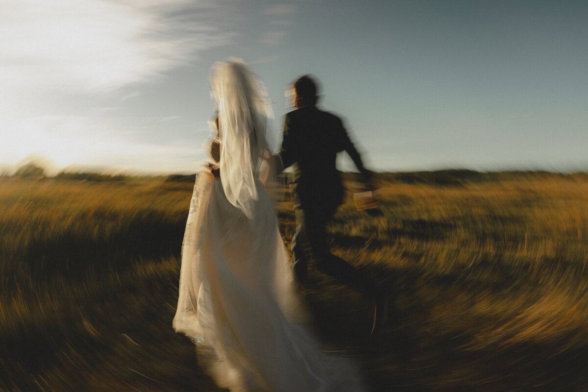 Wedding couple running through an open Alberta field with motion blur
